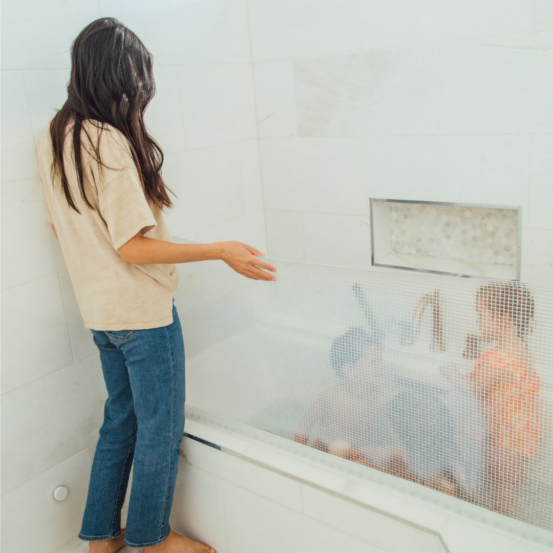 girl is standing and seeing kids who are taking bath in tub